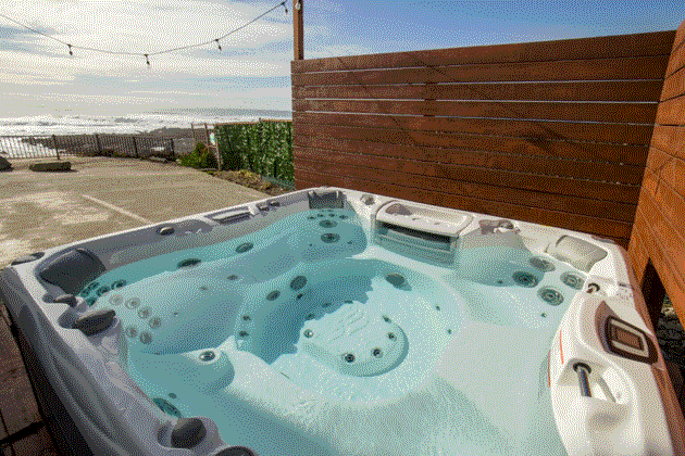 Hot tub on a deck with panoramic ocean views at Redwood's The Black Sands Inn