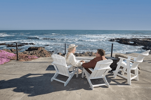 Couple relaxing on a patio with scenic ocean views at Redwood's The Black Sands Inn